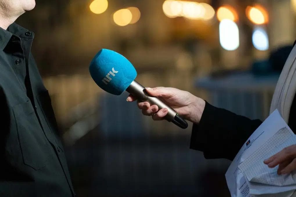 Journalist interviewing a person with an NRK microphone